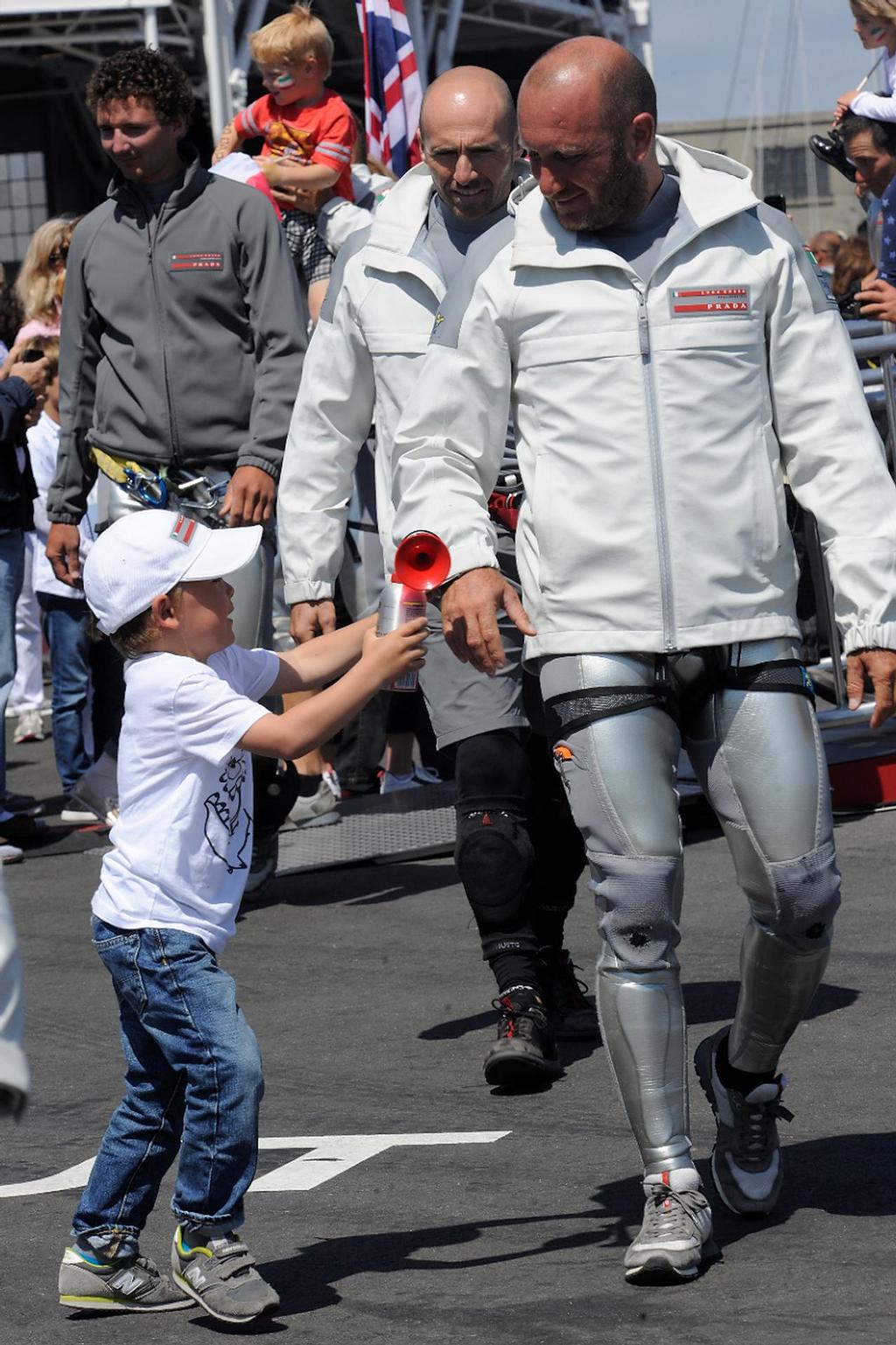 Max Sirena’s son Lorenzo, 4, wants to give his Dad a horn before he goes out to sail on August 21, 2013 at the Louis Vuitton Cup in San Francisco California. ©  SW